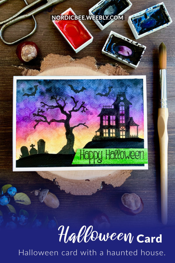 Handmade Halloween card with a watercolour spooky sky at sunset and haunted house, tree and grave yard silhouettes stamped using the Spooky Street stamp set by Newton's Nook Designs.