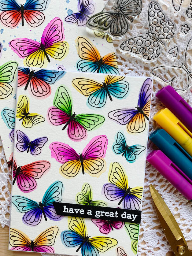 A colourful butterfly card featuring a simple stamped background using individual stamps and messy watercolour technique using water based brush markers.